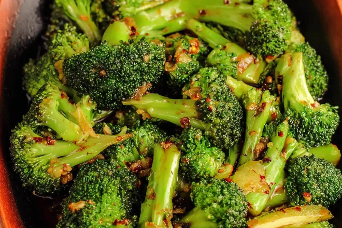 A close-up of vibrant {{ $('Fetch Recipe Data').first().json["Main Keyword"] }} tossed with minced garlic and seasonings.