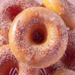 Glossy {{ $('Fetch Recipe Data').first().json["Main Keyword"] }} covered in rainbow sprinkles on a pink background.