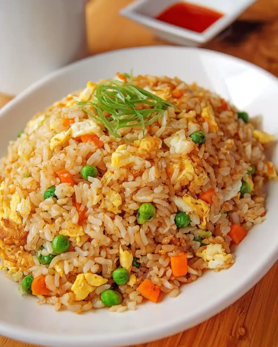 A close-up view of a large white bowl filled with delicious egg fried rice, garnished with fresh green onions.