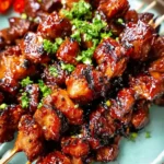 Plate of glossy, caramelized BBQ pork skewers garnished with fresh chopped cilantro.