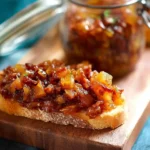 Toasted bread topped with sweet and savory {{ $('Fetch Recipe Data').first().json["Main Keyword"] }}, next to a full glass jar.